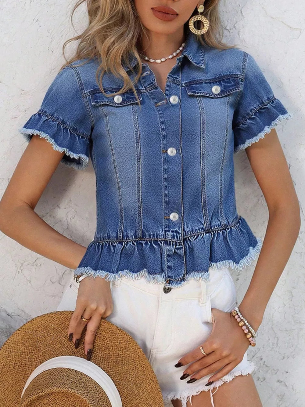 Blue denim trucker jacket with ruffled hem, pearl buttons, and short sleeves.