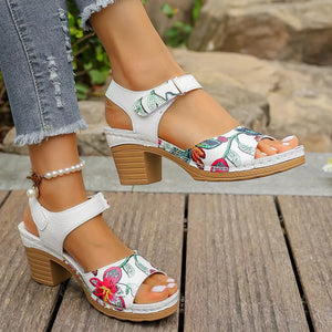 White floral open-toe sandals with adjustable strap and block heel.