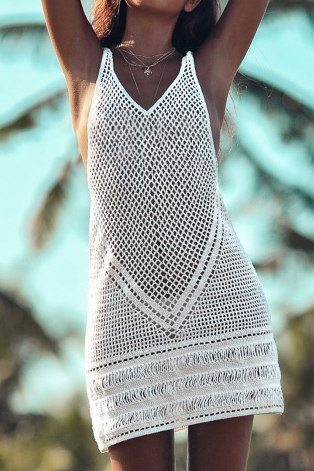 White crochet beach dress with V-neck and fringe hem.