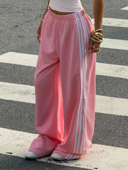 Pink relaxed wide leg sweatpants with white side stripes and elasticated waist.