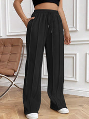 Black pleated palazzo drawstring trousers with a wide leg and pockets.