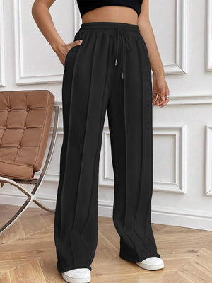 Black pleated palazzo drawstring trousers with a wide leg and pockets.