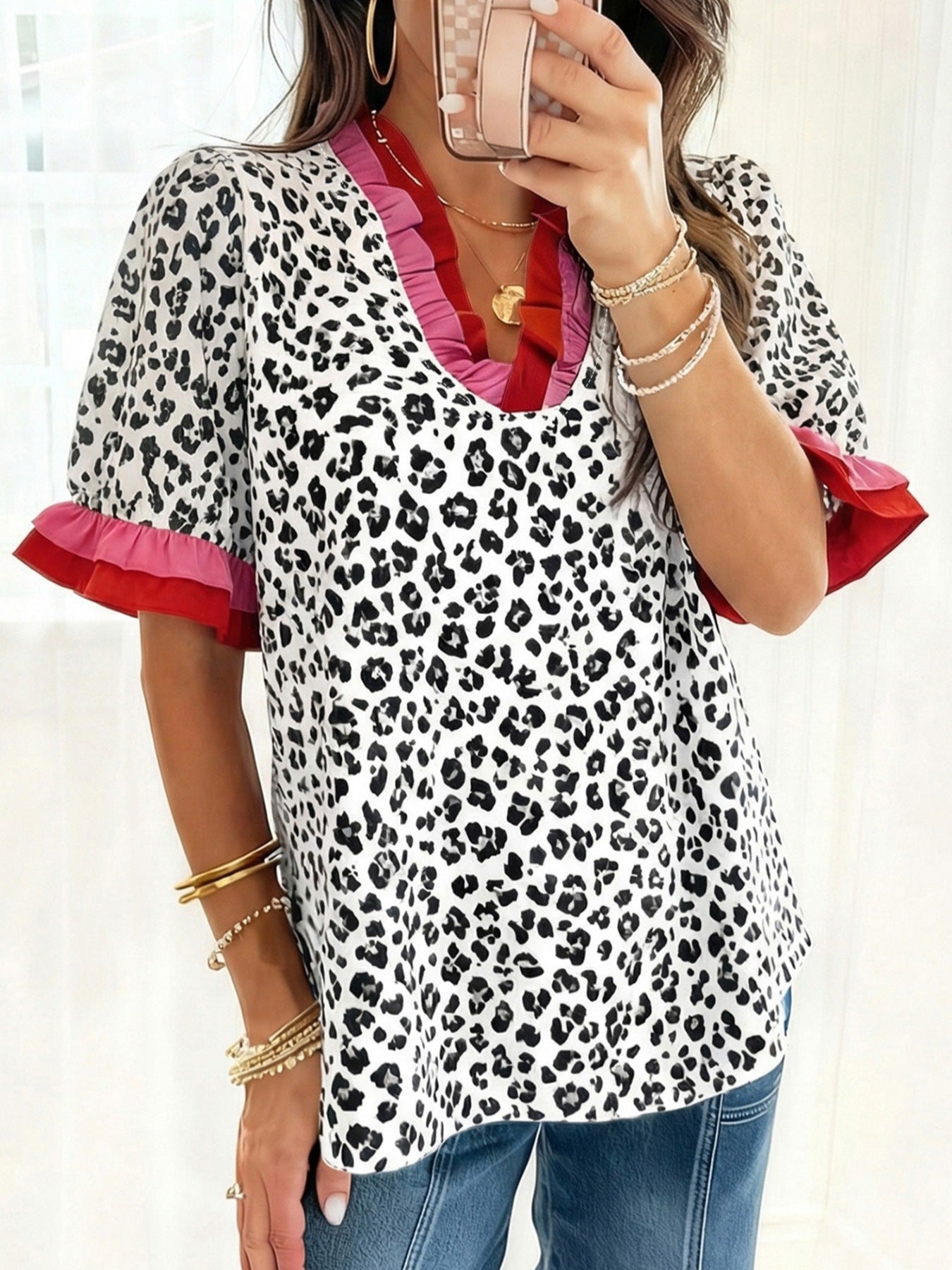 Leopard print blouse with ruffled neckline and sleeves in pink and red.