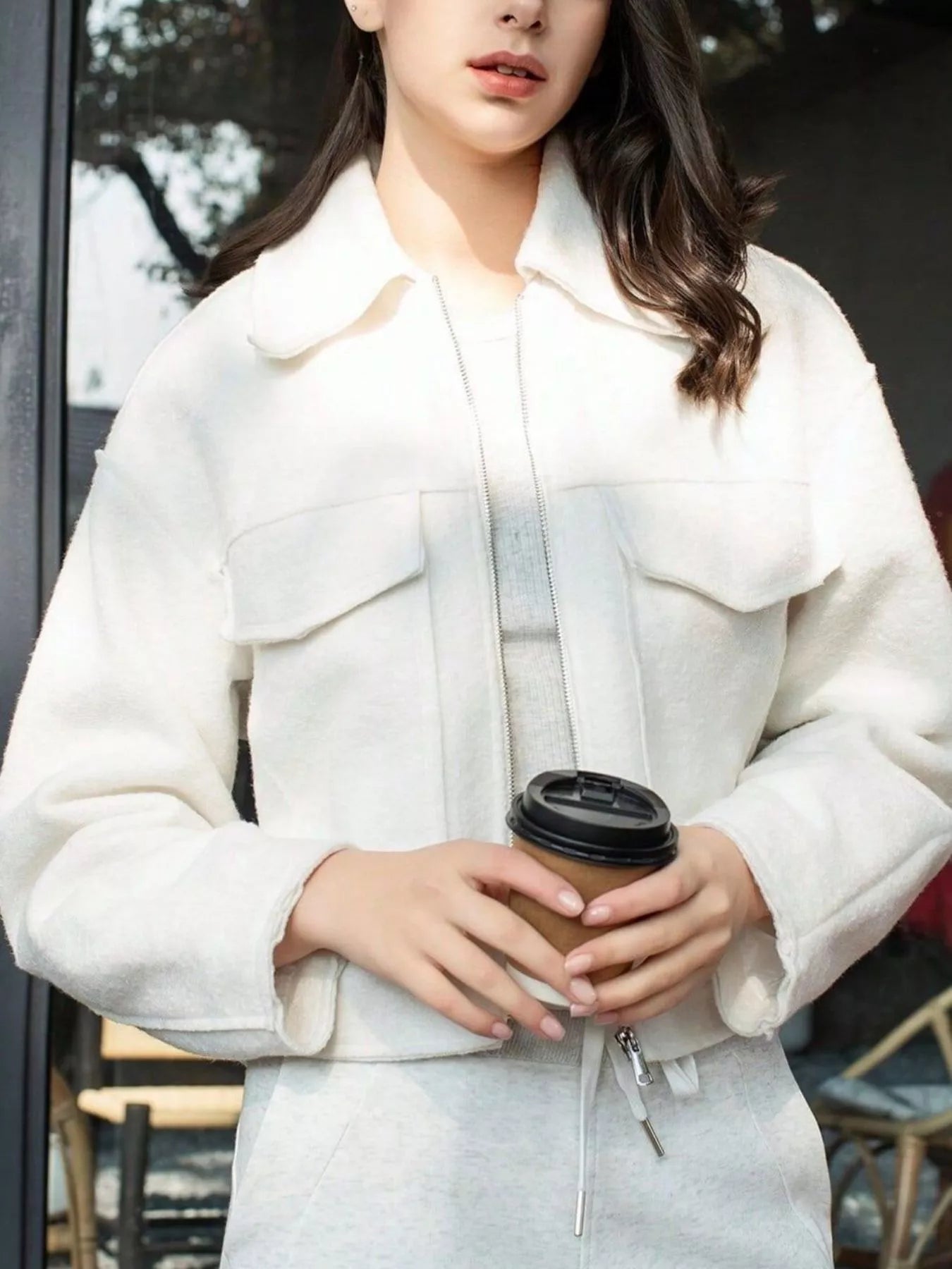 White cropped zip-up jacket with collar and two chest pockets.
