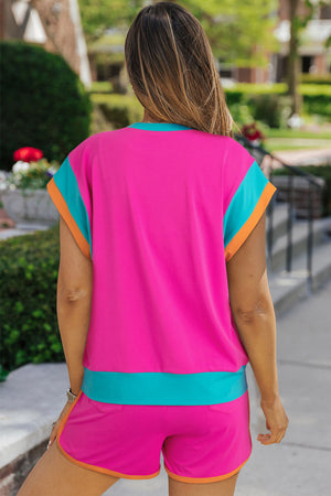 Hot pink co-ord set with teal and orange trim, short sleeves, and shorts.