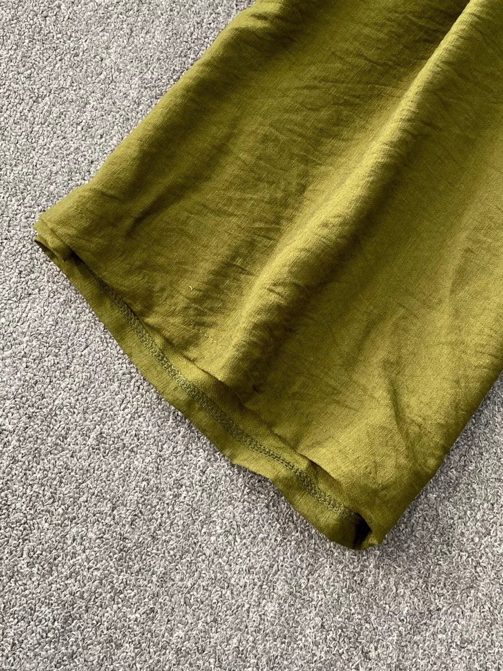 Green wide leg jumpsuit detail showing textured fabric and hem.