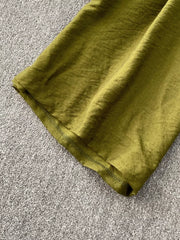 Green wide leg jumpsuit detail showing textured fabric and hem.