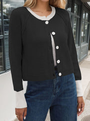Black raglan sleeve knit cardigan with white collar and cuffs, button front.