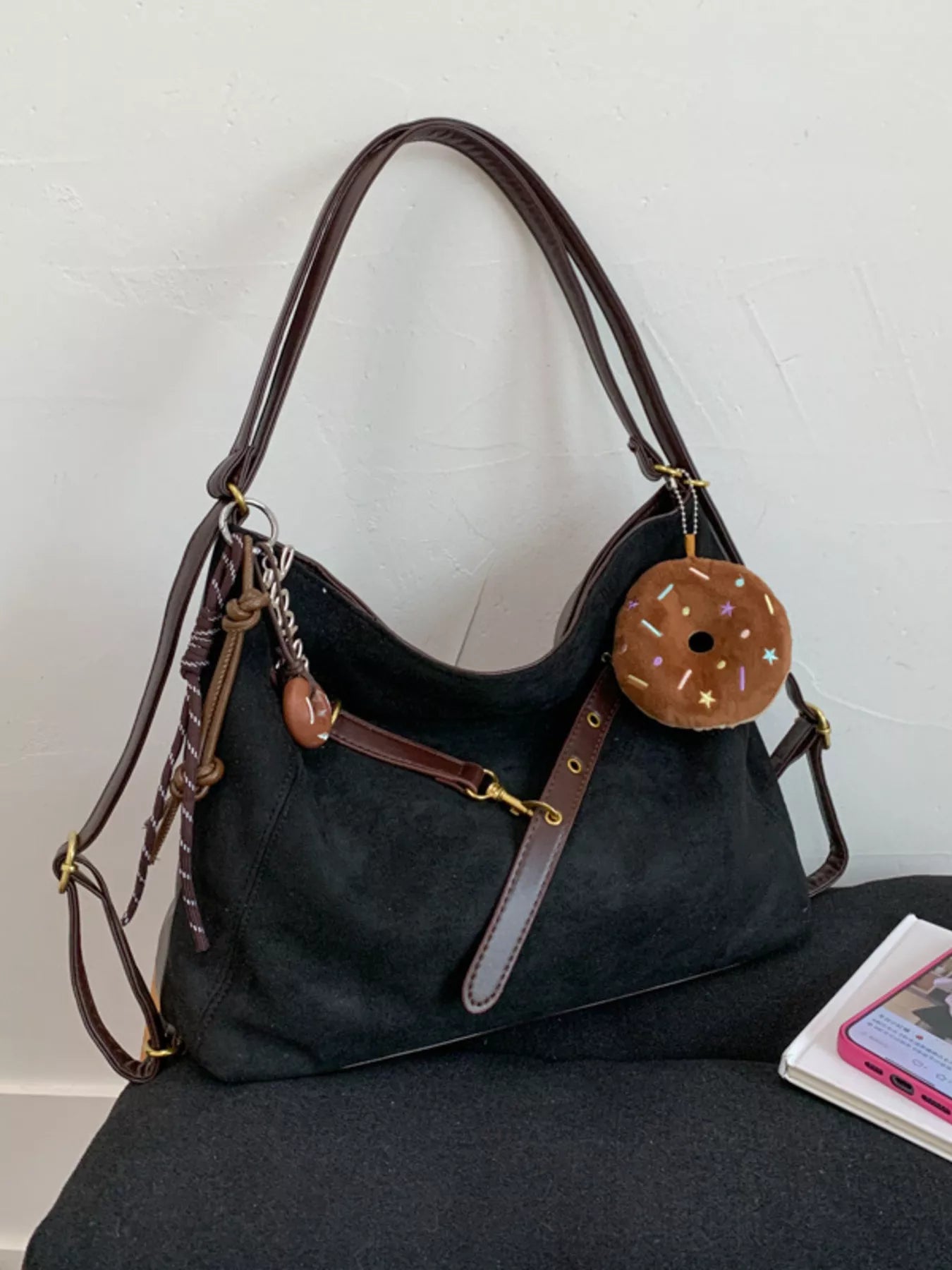 Black hobo bag with adjustable strap and donut charm accessory