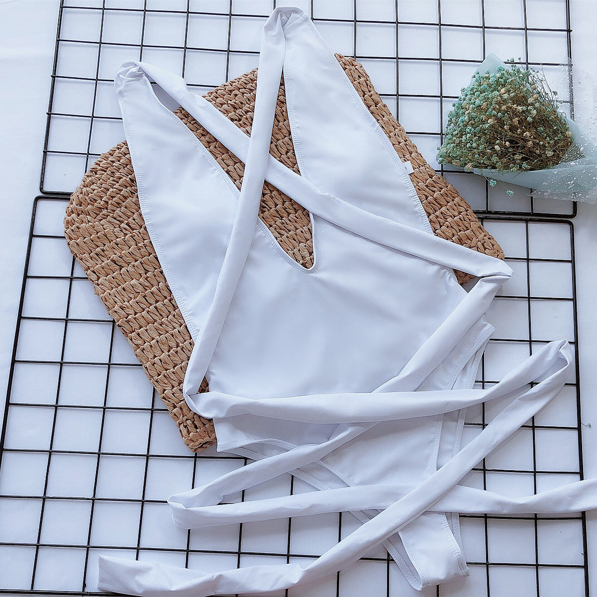 White wrap-around halterneck plunge swimsuit with crisscross straps and tie closure.
