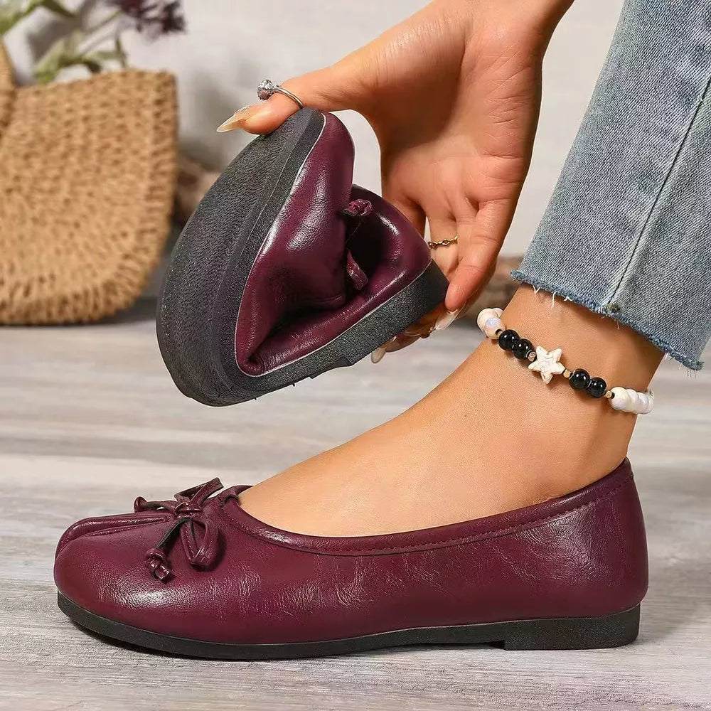 Burgundy bow-embellished tabi slip-on flats shown folded to display flexibility.