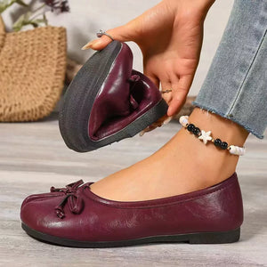 Burgundy bow-embellished tabi slip-on flats shown folded to display flexibility.