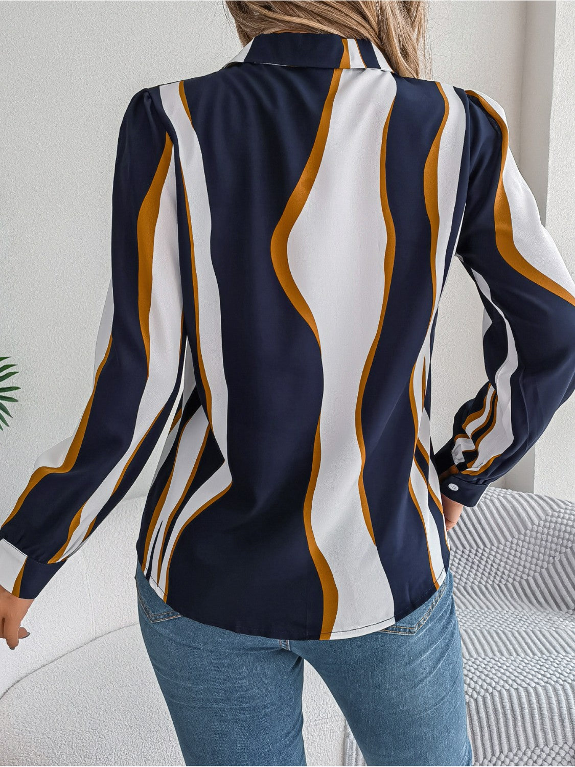Dark blue collared blouse with wavy white and gold stripes, long sleeves.
