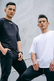 Oversized t-shirts in white and black with subtle chest logos, crew neck, short sleeves.