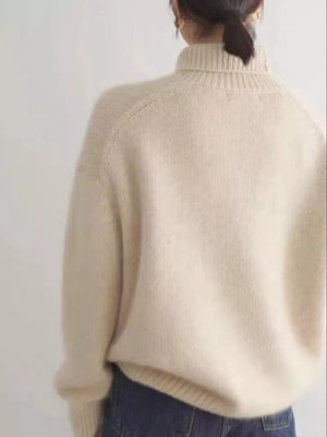 Beige knit turtleneck sweater with dropped shoulders and ribbed details.
