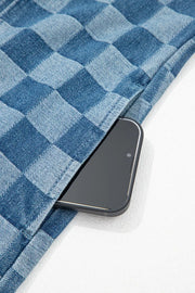 Checkered denim mini dress with frayed hems and a pocket holding a smartphone.