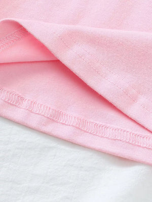 Pink cotton polo shirt hem detail with strawberry embroidery visible.
