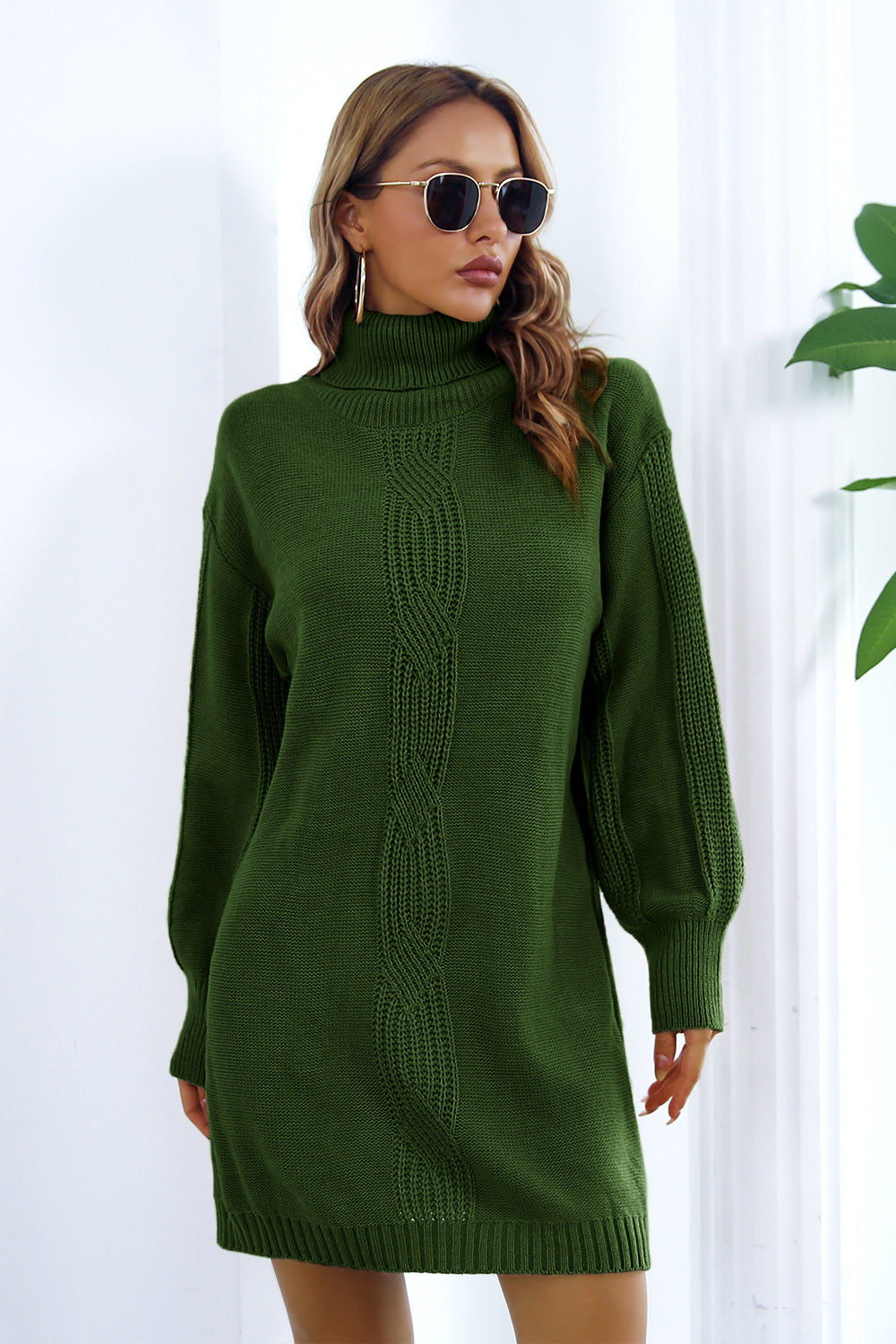 Green cable knit turtleneck sweater dress with blouson sleeves and a ribbed hem.