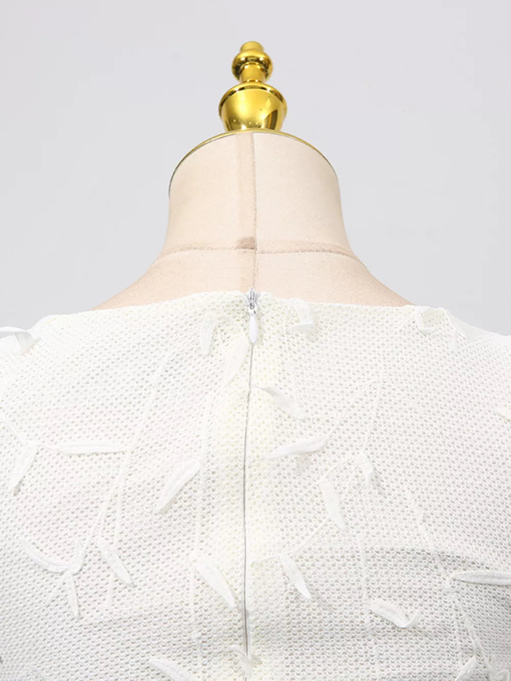 White midi dress with floral applique, boat neck, and zipper detail.
