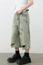 Distressed culotte denim shorts in medium wash with ripped details and a wide leg.