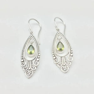 Silver filigree drop earrings with peridot gemstones and ornate scroll details.