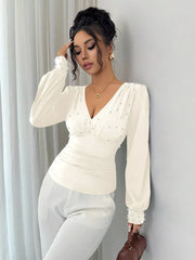 Pearl ruched V-neck blouse in beige with long sleeves and pearl embellishments.