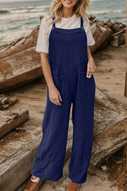 Dark blue textured cotton overalls with square pockets and wide legs, worn with a white t-shirt.