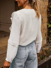 White lace ruffle V-neck blouse with long sleeves and tiered cuff detail.