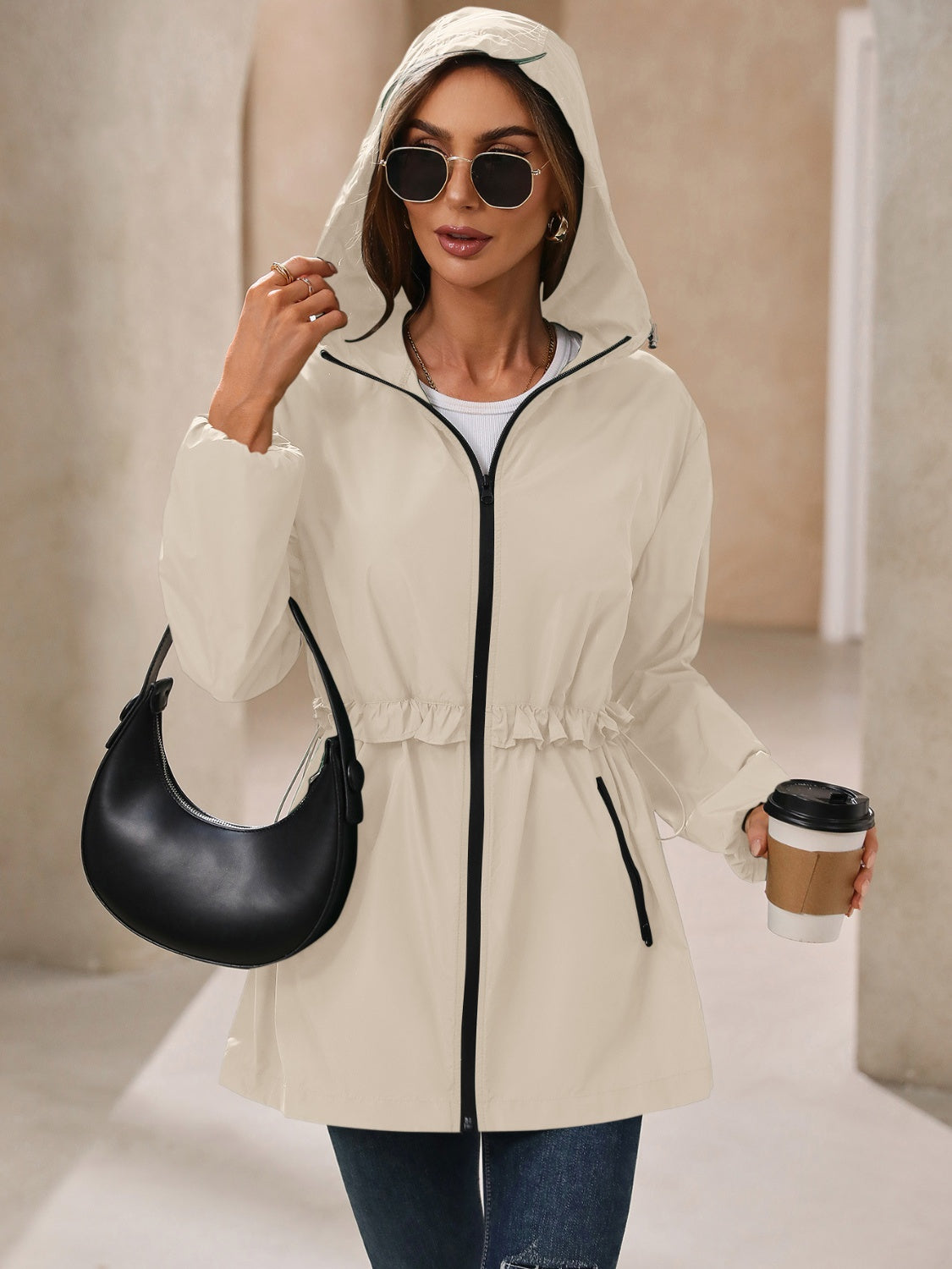 Cream hooded windbreaker jacket with ruffled waistline and black trim.