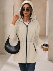 Cream hooded windbreaker jacket with ruffled waistline and black trim.