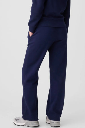 Navy relaxed-fit lounge trousers with drawstring and pockets, worn with sneakers.