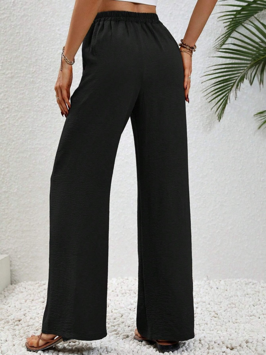 Black textured palazzo trousers with drawstring waist and wide legs.