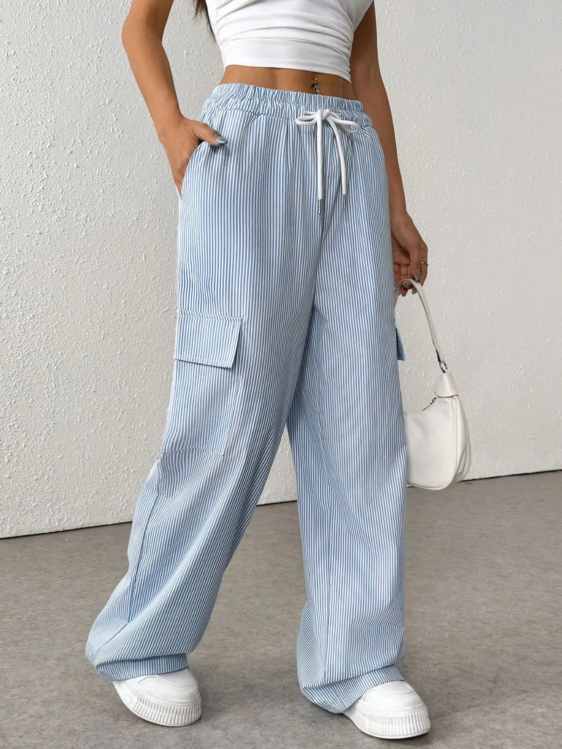 Light blue pleated cargo palazzo trousers with white pinstripes and drawstring waist.