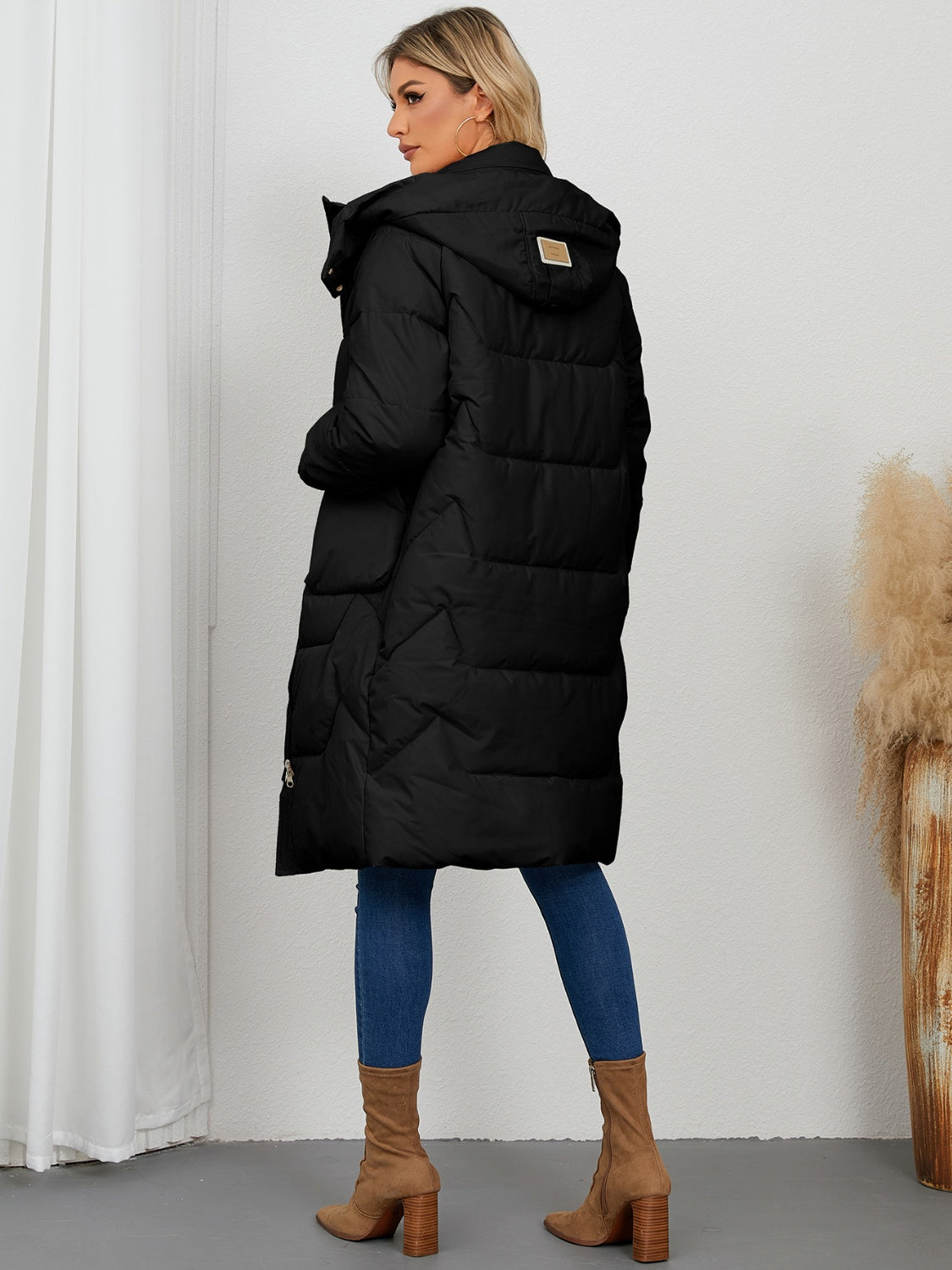 Black quilted puffer parka with hood and buckle detail, long length.