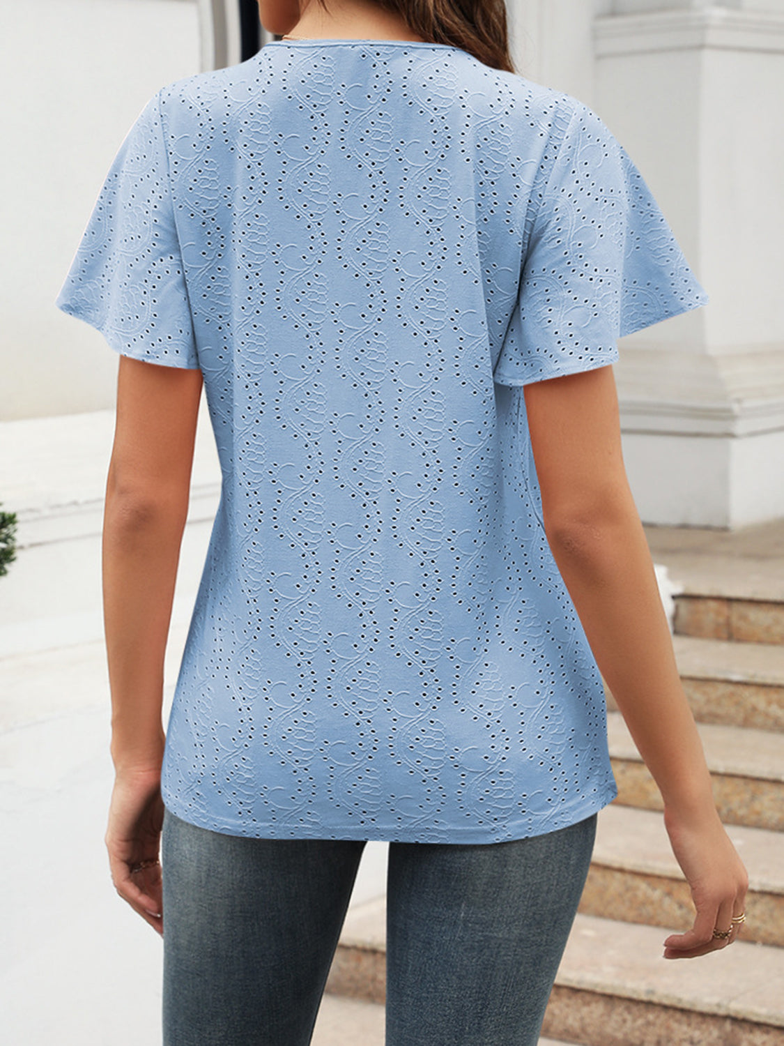 Light blue eyelet blouse with flutter sleeves and a V-neck, shown from the back.