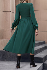 Dark green midi dress with smocked bodice, long sleeves, and flared skirt.