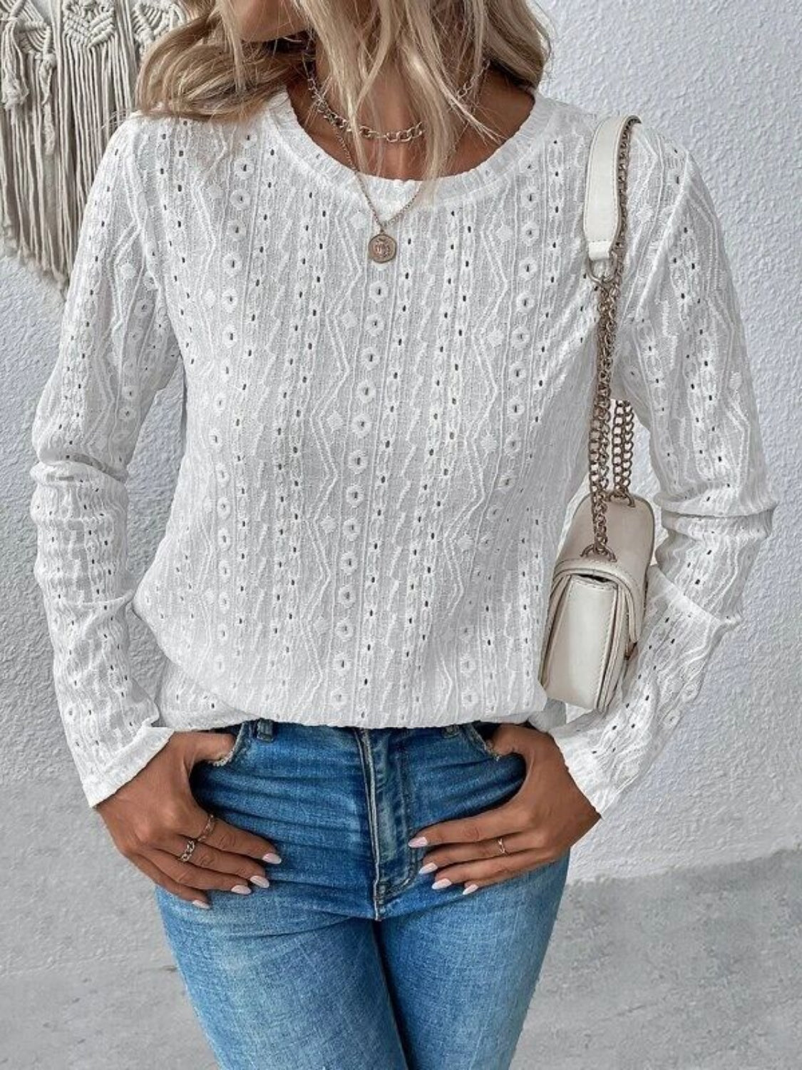 White geometric eyelet long sleeve knit top with crew neck.