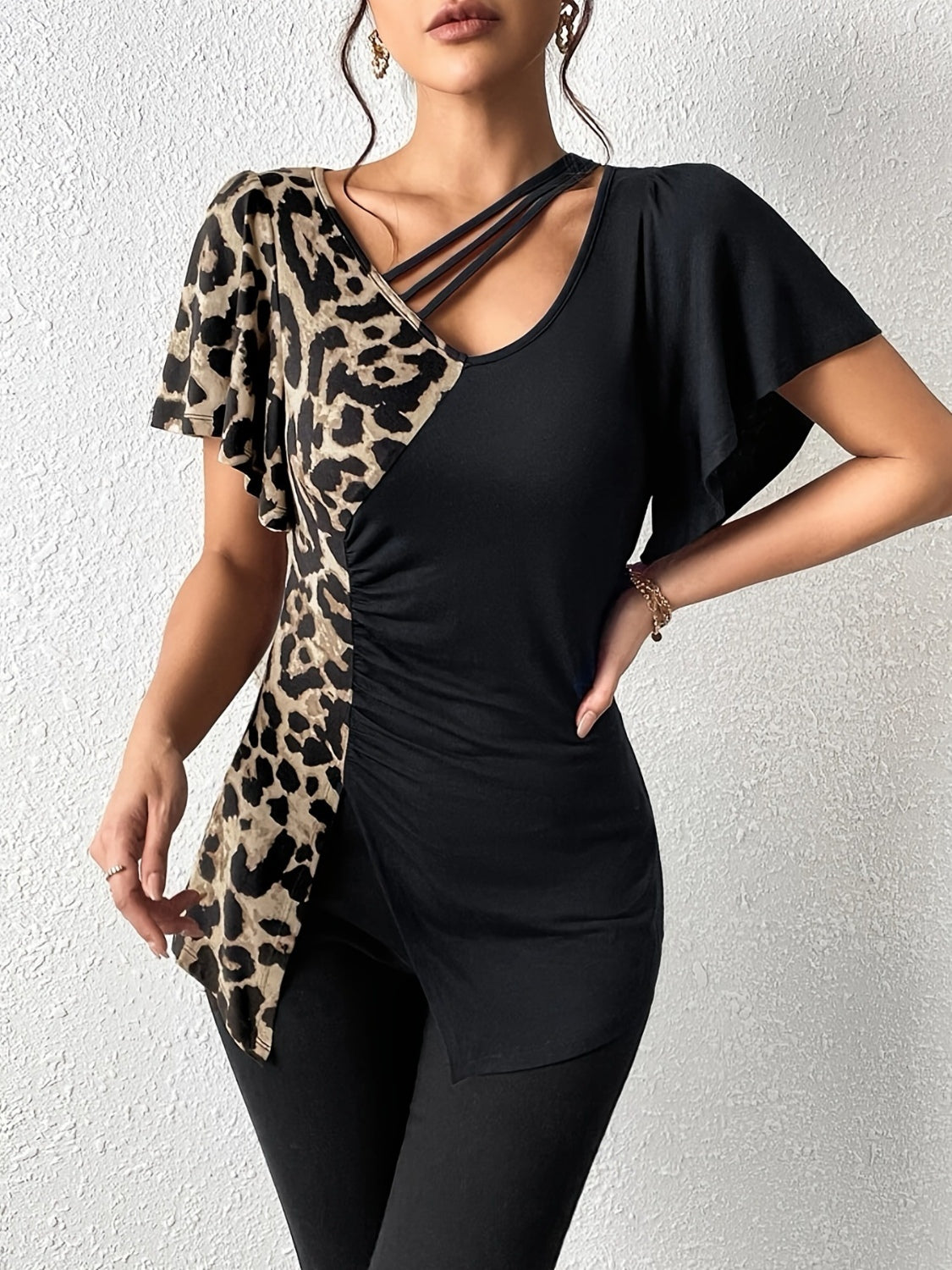 Asymmetric black top with leopard print panel, cutout neckline, and ruched detail.