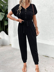 Black utility jumpsuit with short sleeves, V-neck, button front, tie waist and pockets.