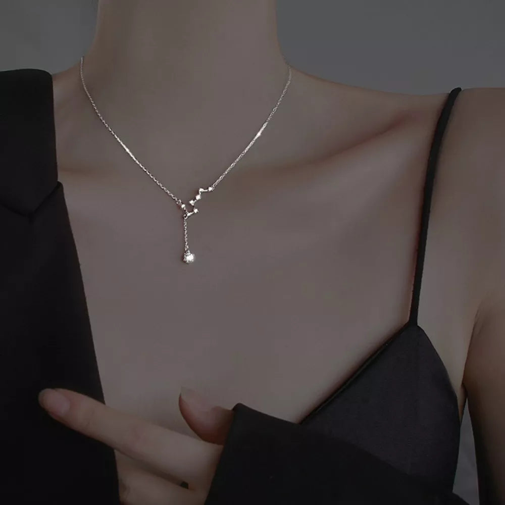Sterling silver necklace with constellation design and dangling crystal pendant.