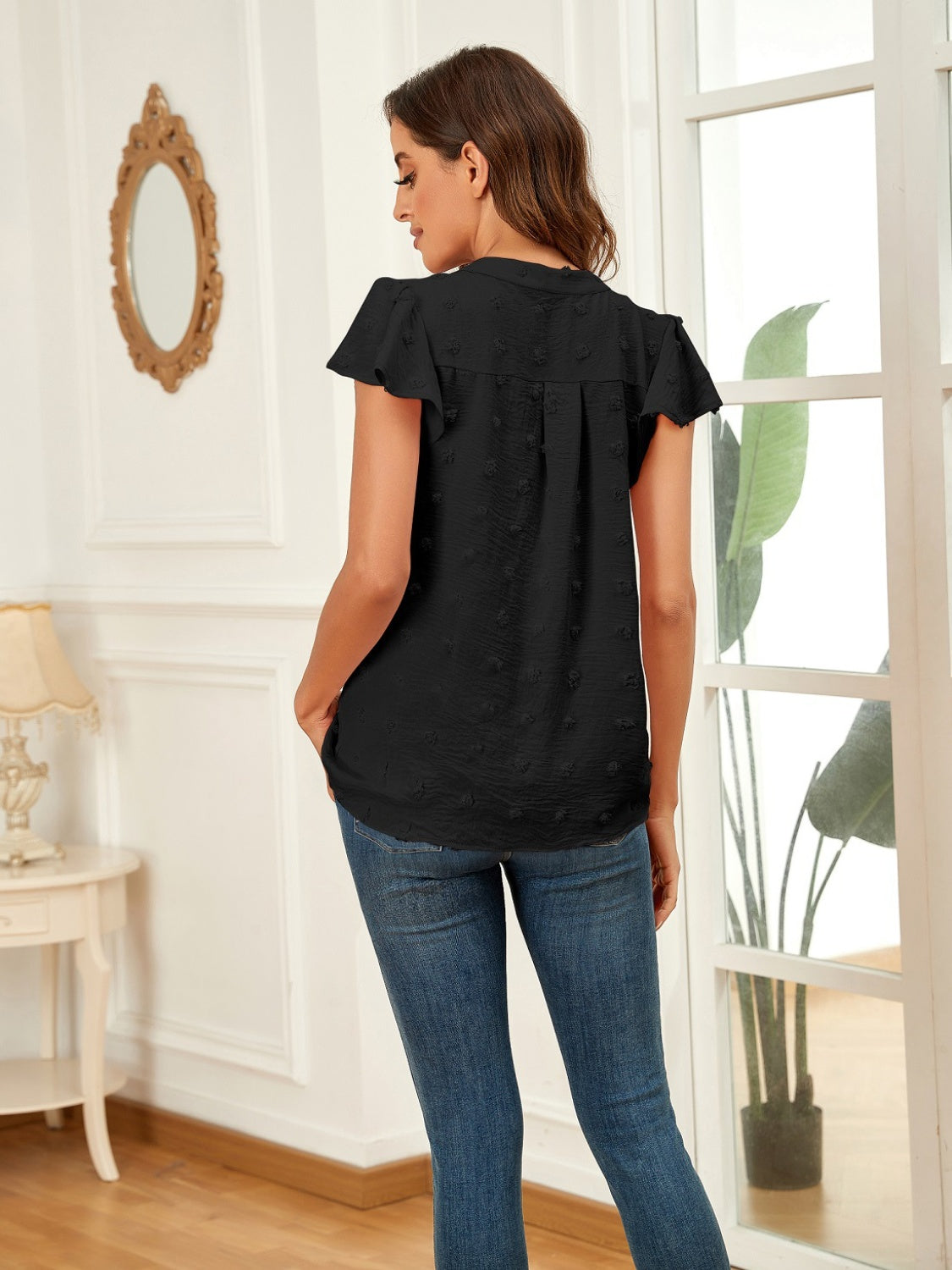 Black flutter sleeve swiss dot blouse with V-neck and ruffled details.
