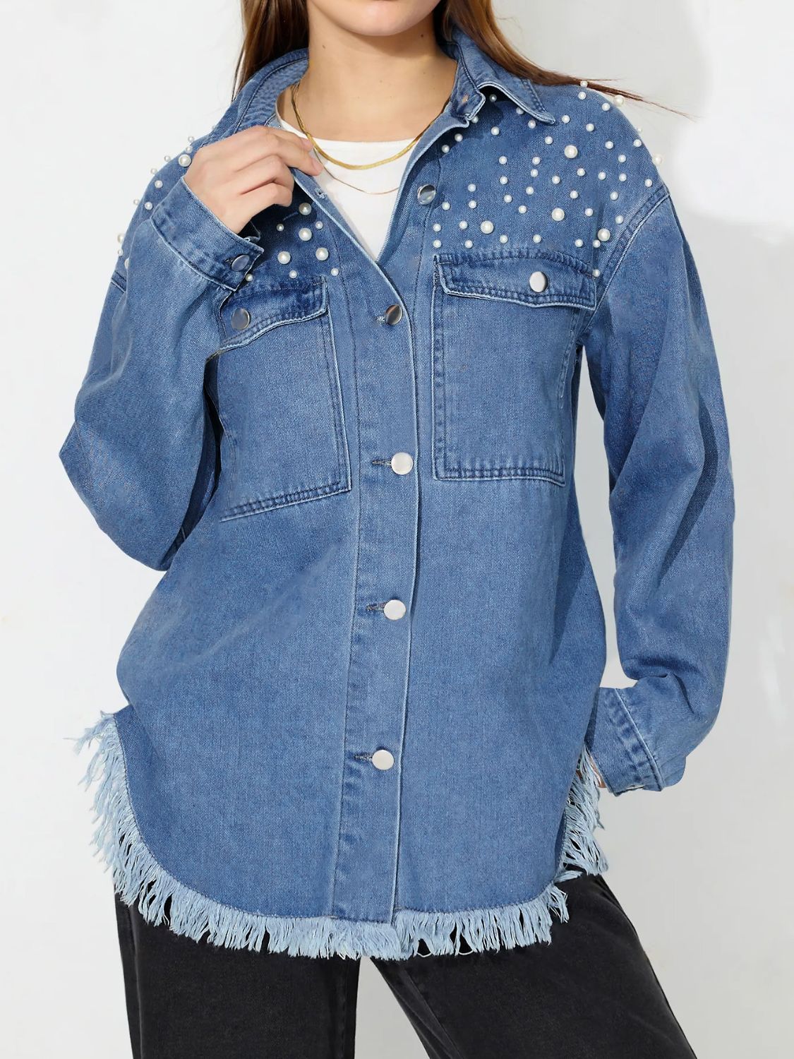 Medium wash denim shirt with pearl embellishments and frayed hem.
