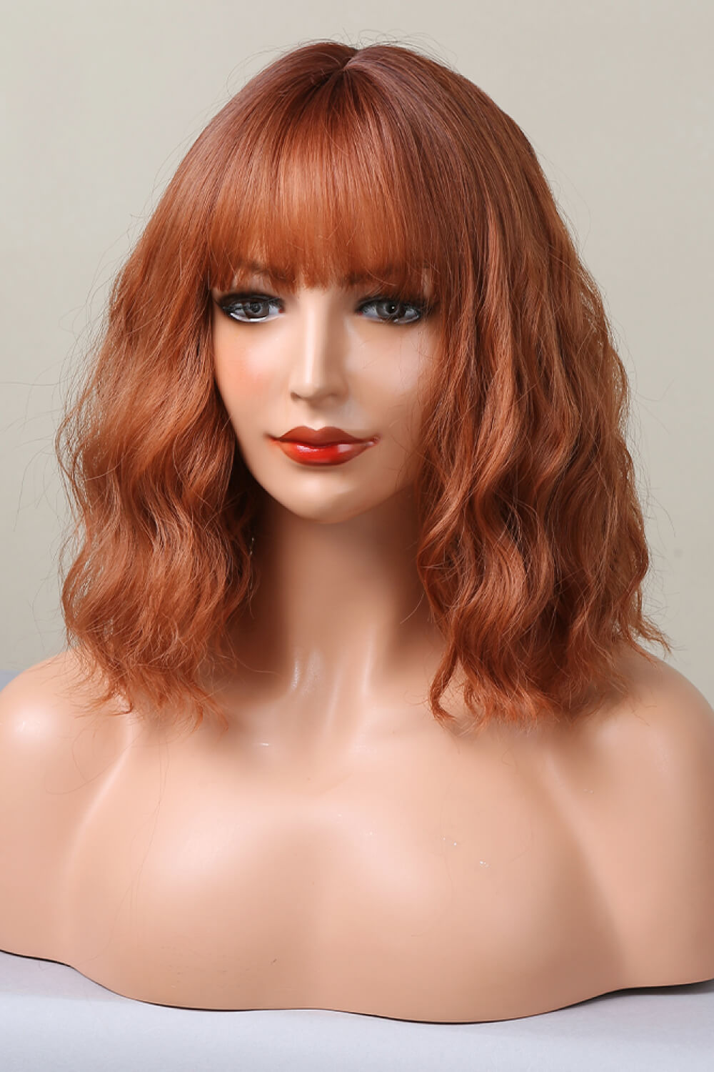 Rose Quartz bob wig in ochre with bangs and wavy texture.
