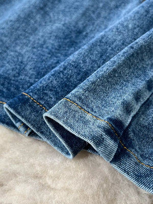 Blue denim fabric with visible stitching detail and frayed edges.