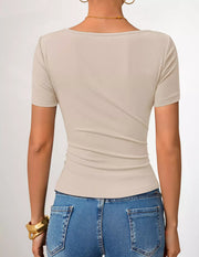 Beige asymmetrical fitted maternity t-shirt with short sleeves and a scoop neckline.