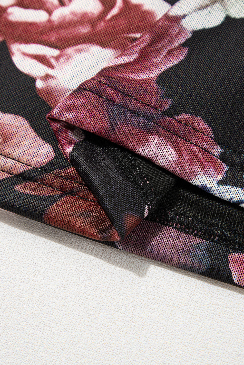 Black mesh blouse with a romantic floral print and visible seams.