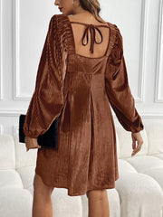 Brown velvet mini dress with square neckline, puff sleeves, and back tie detail.