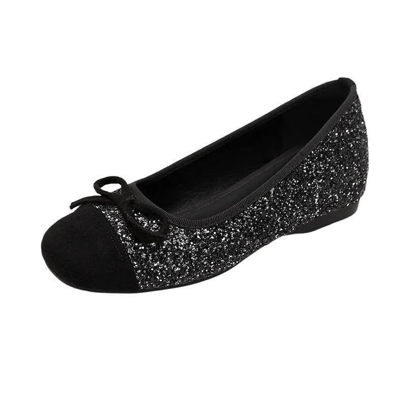 Black glitter ballet flats with a suede cap toe and bow detail.