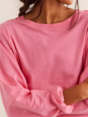 Pink long sleeve crop top with crew neck and raw hem detail