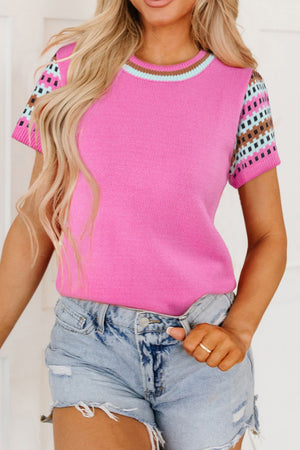 Fuchsia pink knit top with geometric patterned sleeves and striped neckline.